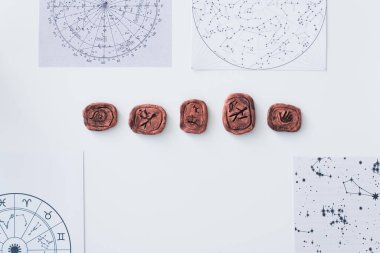 top view of celestial charts and clay runes on white table