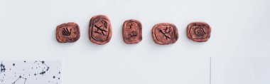 top view of clay runes near celestial charts on white surface, banner