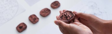 partial view of cropped fortune teller holing clay rune, banner clipart
