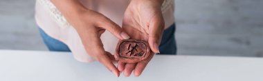 cropped view of clay rune in hands of cropped fortune teller, banner