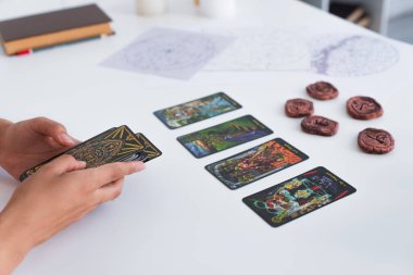 KYIV, UKRAINE - JUNE 29, 2022: cropped view of fortune teller near tarot cards and blurred celestial charts