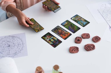 KYIV, UKRAINE - JUNE 29, 2022: high angle view of cropped fortune teller predicting on tarot cards near clay runes