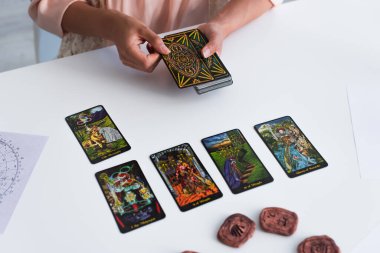 KYIV, UKRAINE - JUNE 29, 2022: top view of tarot cards on table near cropped fortune teller predicting at home