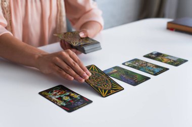 KYIV, UKRAINE - JUNE 29, 2022: partial view of fortune teller laying out tarot cards on table