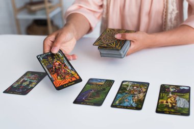 KYIV, UKRAINE - JUNE 29, 2022: partial view of woman predicting on tarot cards at home
