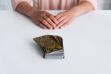 KYIV, UKRAINE - JUNE 29, 2022: selective focus of tarot cards near cropped fortune teller on blurred background