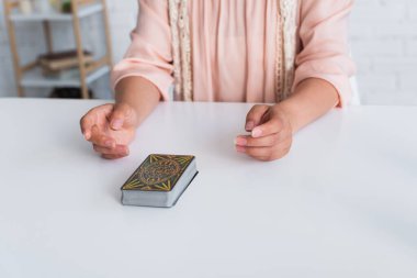 KYIV, UKRAINE - JUNE 29, 2022: cropped view of oracle near deck of tarot cards on table