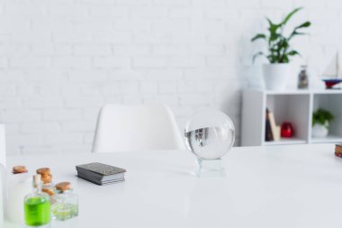 KYIV, UKRAINE - JUNE 29, 2022: crystal ball near tarot cards and bottles with essential oils on white table