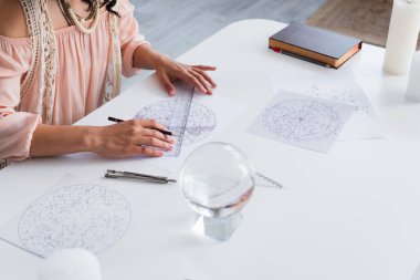 partial view of young astrologer drawing cosmic charts near magic crystal