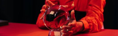 cropped view of blurred fortune teller predicting near crystal ball isolate on black, banner
