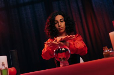 medium predicting future near crystal ball on dark draped background 