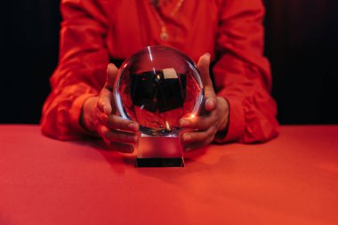 partial view of blurred wizard near crystal ball isolated on black