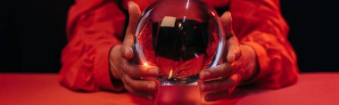 selective focus of crystal ball near cropped fortune teller isolated on black, banner