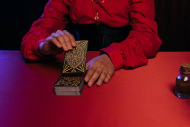 KYIV, UKRAINE - JUNE 29, 2022: partial view of woman predicting on tarot cards on table isolated on black