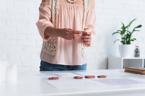 partial view of astrologer holding clay runes near celestial maps 