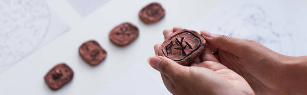 partial view of cropped fortune teller holing clay rune, banner