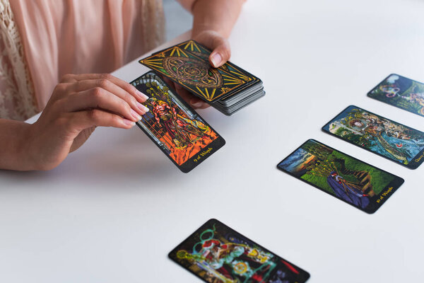 KYIV, UKRAINE - JUNE 29, 2022: partial view of predictor holding tarot cards during spiritual session