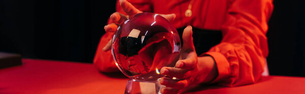 cropped view of blurred fortune teller predicting near crystal ball isolate on black, banner