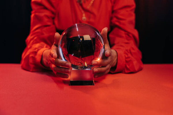 partial view of blurred wizard near crystal ball isolated on black