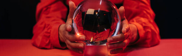 selective focus of crystal ball near cropped fortune teller isolated on black, banner