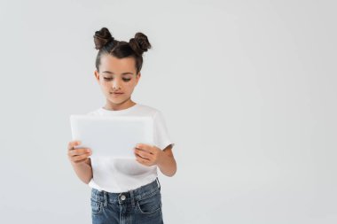 adorable girl with glitter stars on cheeks using digital tablet isolated on grey