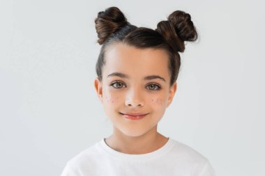 portrait of cheerful child with lip gloss and glitter stars on cheeks looking at camera isolated on grey