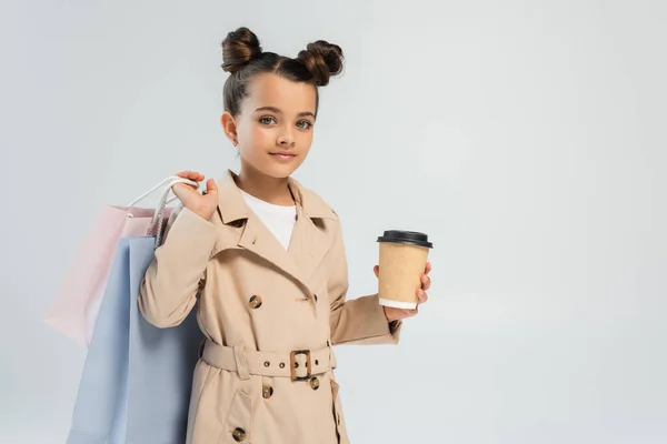 Adorable Girl Trench Coat Holding Takeaway Drink Shopping Bags Isolated — 스톡 사진