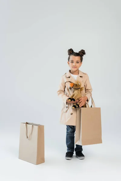 Full Length Cheerful Kid Trench Coat Jeans Holding Soft Toy — Foto de Stock