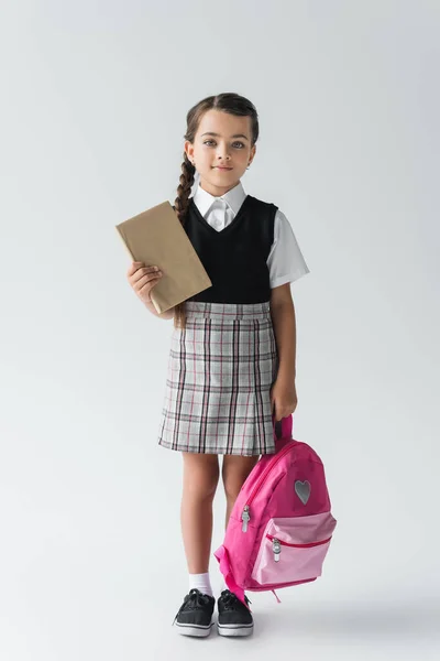 Full Length Adorable Schoolgirl Uniform Holding Pink Backpack Book Grey — Stockfoto