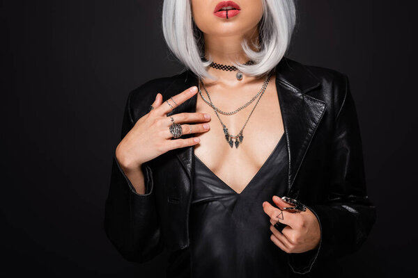 cropped view of sexy ash blonde woman in leather jacket with decollete isolated on black