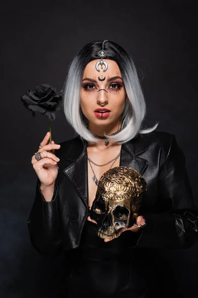 灰白金发碧眼的女人 黑漆漆的背景上挂着黑色的玫瑰和金色的骷髅 — 图库照片
