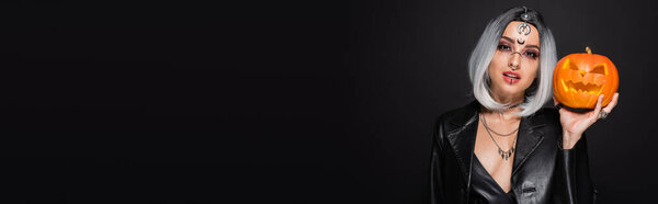 зола блондинка с макияжем в стиле ведьмы и резной тыквы изолированы на черном, баннер
