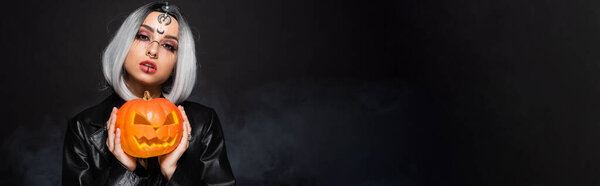 женщина в костюме ведьмы Хэллоуин держа Джек фонарь на черном фоне, баннер