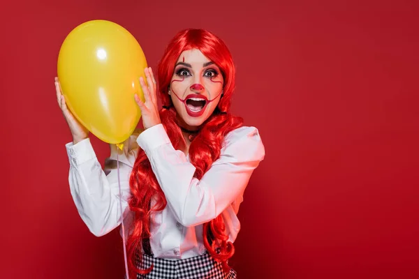 Shocked Woman Clown Makeup Holding Yellow Balloon Screaming Isolated Red — Stock Photo, Image