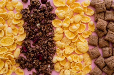 Çeşitli kahvaltılık mısır gevreğinin üst görüntüsü. Puf gevreği ve pembeleşmiş granola. 