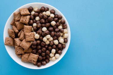 Lezzetli mısır gevreği topları ve mavi üzerine izole edilmiş puf börekleri olan kasenin üst görüntüsü.