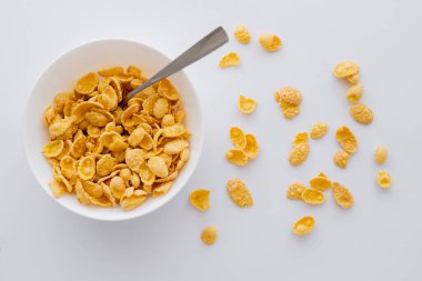 Mısır gevreği ve kaşıkla beyaza izole edilmiş kasenin üst görüntüsü.