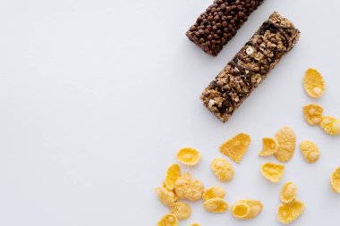 Lezzetli granola barlarının yakınındaki gevrek mısır gevreğinin beyaz üzerine izole edilmiş üst görüntüsü 