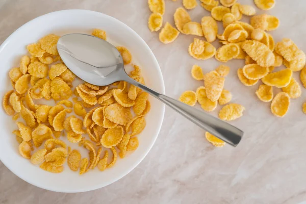 top view of bowl with corn flakes and organic milk on marble surface