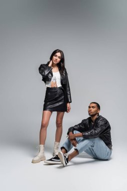 Gri giyinmiş Afro-Amerikan bir adamın yanında duran, sonbahar kıyafetli şık bir kadın.