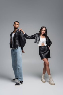 Uzun boylu, deri elbiseli, çizmeli, şık, Afro-Amerikan Gri Giyimli Adam 'ın omzuna dokunan genç bir kadın.