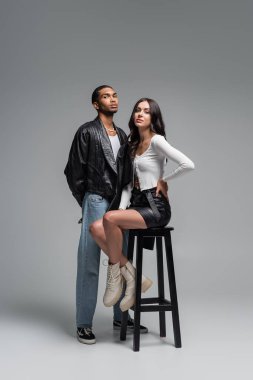 Uzun boylu, deri etekli bir kadın şık afro-amerikan erkeğinin yanındaki yüksek sandalyede oturuyor. 