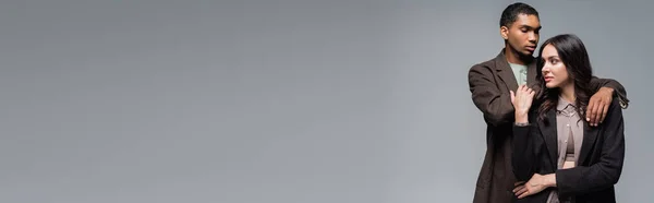 Молодий Афроамериканський Чоловік Обіймає Брюнетку Блістері Ізольовано Сірому Банер — стокове фото