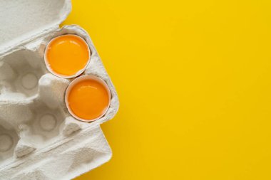 Sarı arka planda yumurta tepsisindeki kabuklu taze yumurta sarılarının üst görüntüsü 
