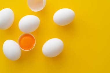 Sarı arka planda yumurtaların yanında kabuklu doğal yumurta sarısı manzarası 