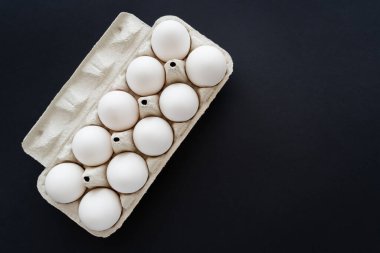 Karton kutudaki tavuk yumurtaları siyah renkte izole edilirken organik görünümün üst görüntüsü 