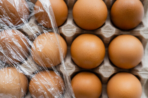 Top view of cellophane on brown chicken eggs in container 
