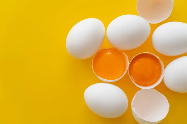 Bovenaanzicht Van Natuurlijke Eieren Dooiers Schelpen Gele Achtergrond Met Kopieerruimte — Stockfoto