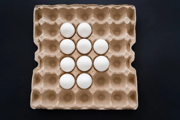 Top view of white eggs in carton package isolated on black