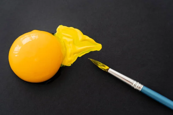 筆に近い卵黄のトップビューと黒の背景にペイント — ストック写真